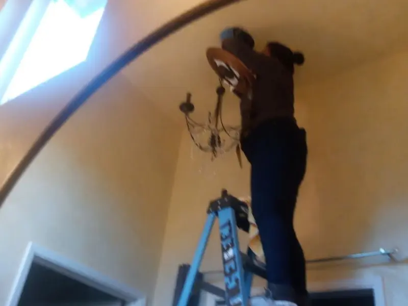 Electrician installing a chandelier in a Germantown residence